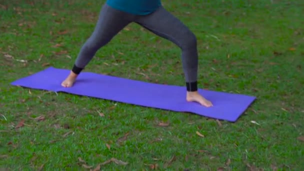 Молода жінка займається вправами йоги в тропічному парку — стокове відео