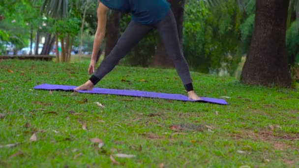 Ung kvinna gör yogaövningar i en tropisk park — Stockvideo