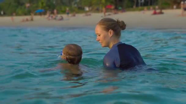 女子游泳指导员教小男孩在海里游泳 sundet — 图库视频影像