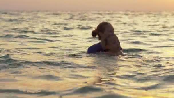 Mujer instructora de natación enseña a niño a nadar en un mar durante un atardecer — Vídeos de Stock