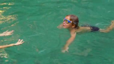 Genç kadın yüzme dersi öğretmek bir yürümeye başlayan çocuk bir havuzda yüzmeyi