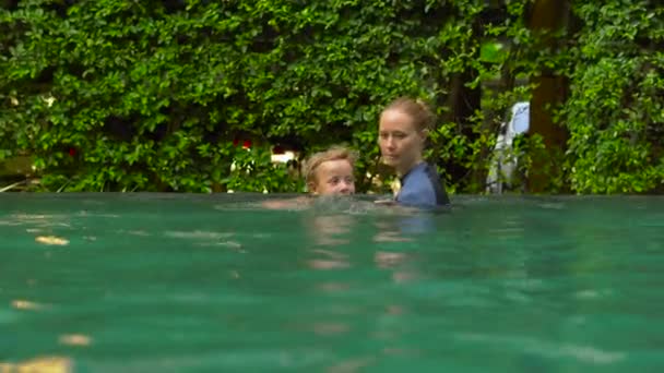 Jovem instrutora de natação ensina um menino criança a nadar em uma piscina — Vídeo de Stock