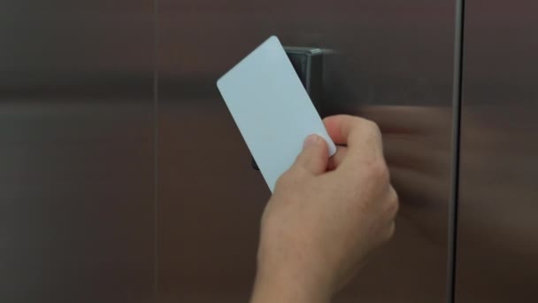 Женщина прикрепила в лифте свою пластиковую карточку ключа, чтобы разблокировать возможность войти в его квартиру — стоковое видео