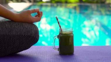 Meditasyon sırasında bir kadının elleri closeup ıspanak, portakal ve muz havuz zemin üzerine yeşil smoothies ile