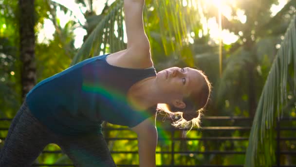 Молодая женщина делает упражнения на крыше дома в тропиках — стоковое видео