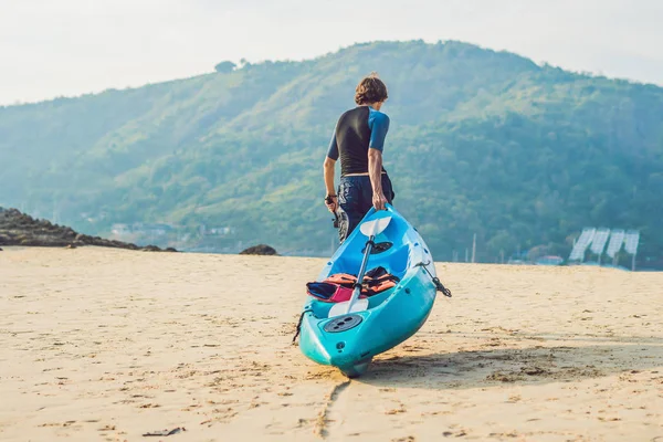 Jeune homme portant son kayak le long du rivage — Photo