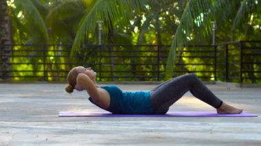 Tropik bölgelerde bir evin çatısında egzersiz yapan genç bir kadın.