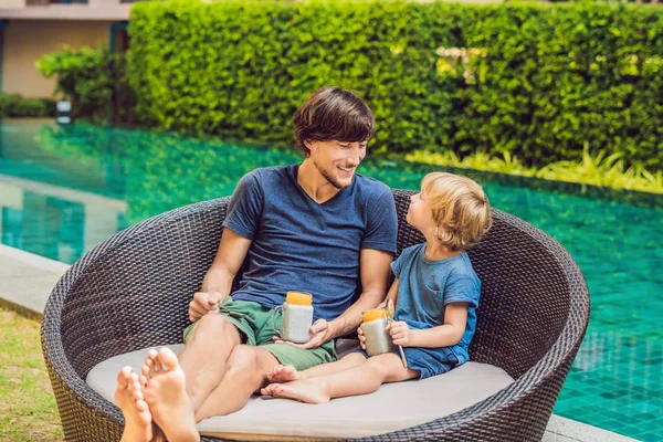 Father and son eat dessert with chia seeds and mangoes by pool in morning. Healthy eating, vegetarian food, diet and people concept.