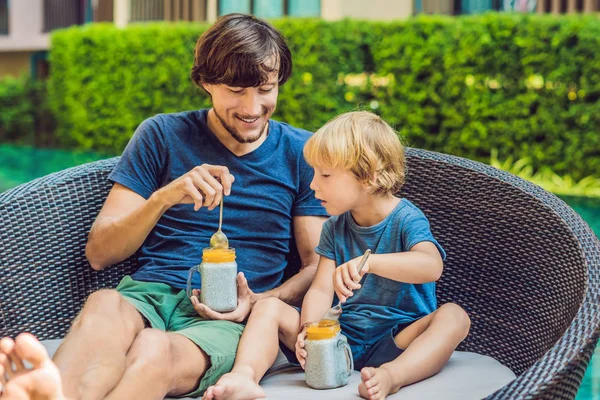 父亲和儿子早上在游泳池边吃着嘉籽和芒果的甜点 健康饮食 饮食和人的观念 — 图库照片