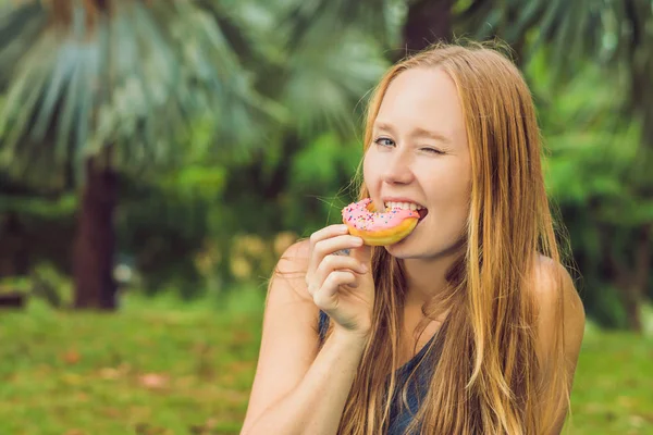 Retrato Uma Jovem Mulher Comendo Donut Contra Fundo Planta — Fotografia de Stock