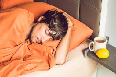 Yatakta yatarken, çay içme ve sıcaklık termometre ile ölçme duygu soğuk, genç adam