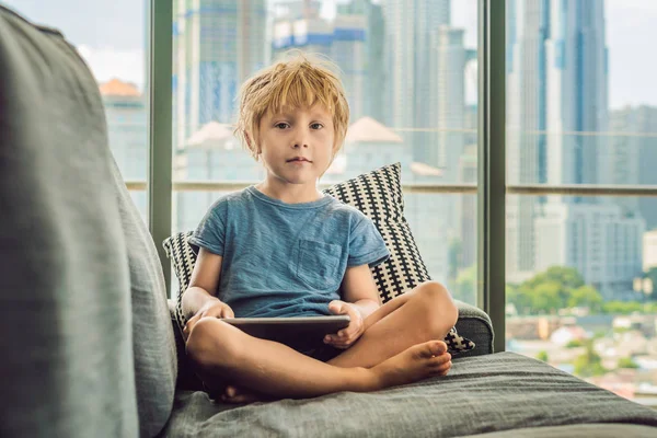 Boy Pomocí Tabletu Doma Gauči Pozadí Okna Mrakodrapy Moderní Děti — Stock fotografie