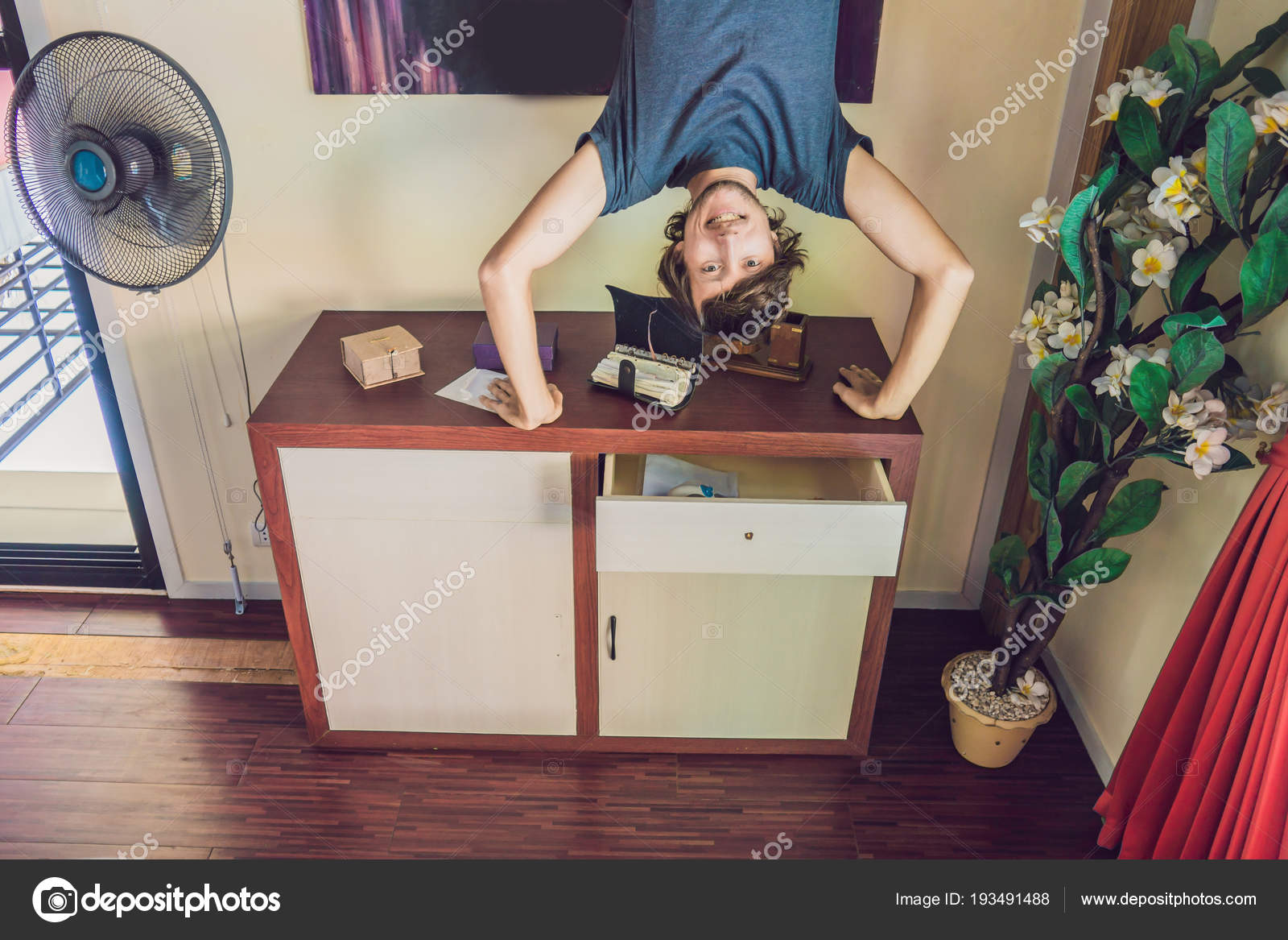 A Man Stands On His Hands Upside Down In The Living Room
