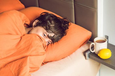 Yatakta yatarken, çay içme ve sıcaklık termometre ile ölçme duygu soğuk, genç adam