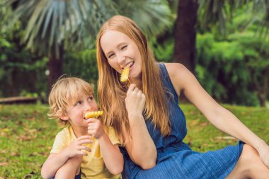 Anne ve oğlu piknik park vardı. Sağlıklı meyve - mango, ananas ve kavun yemek. Çocuk sağlıklı yemek yemek.