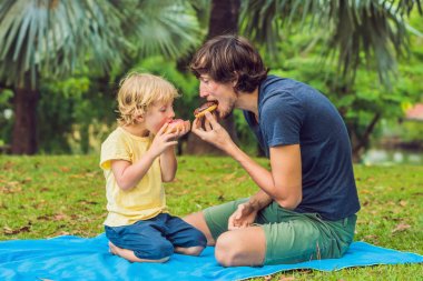 Baba ve oğul çörek parkta yiyorsun. Aile içinde zararlı beslenme