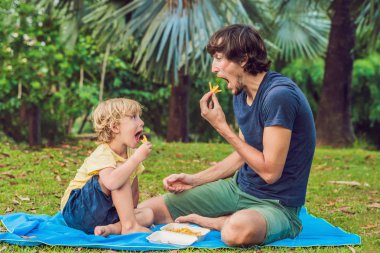 Sevimli çocuk babasıyla ketçap ile kızarmış patates patates yiyor. 