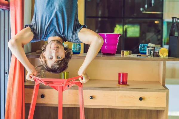 Un hombre está de pie sobre sus manos boca abajo en la cocina — Foto de Stock