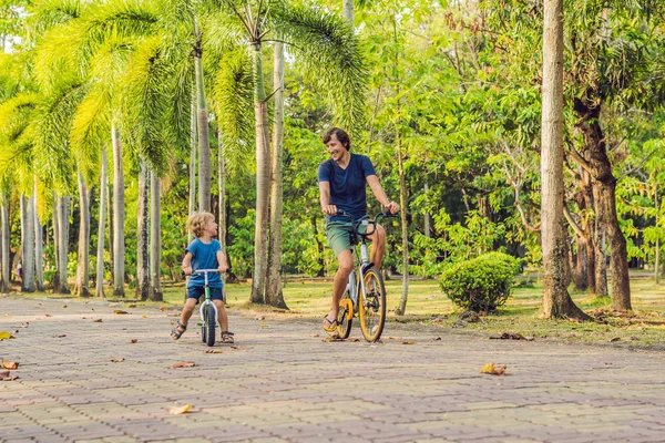 Счастливая семья ездит на велосипедах и улыбается. Отец на велосипеде, а сын на велосипеде — стоковое фото