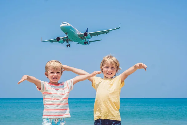 Два счастливых мальчика на пляже и посадочный самолет. Путешествие с детской концепцией — стоковое фото