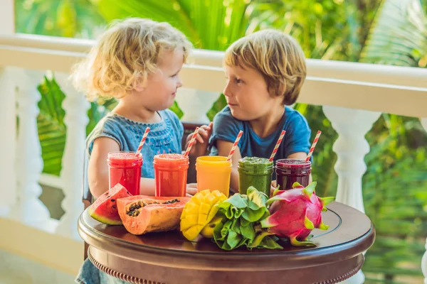 I bambini bevono colorati frullati sani.. Anguria, papaia, mango, spinaci e frutta del drago. Frullati, succhi di frutta, bevande, varietà di bevande con frutta fresca su un tavolo di legno — Foto Stock