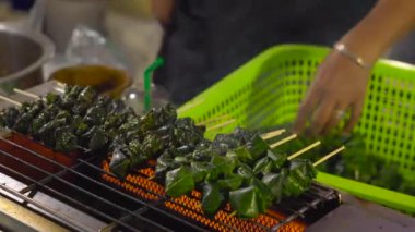 Tayland gece piyasada bir avucunda bir kıyma bir Barbekü sarılmış getirme işlemi bırakır. Tay gıda kavramı. Asya gıda kavramı
