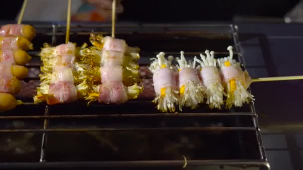 Διαδικασία της λήψης του μπάρμπεκιου μια μανιτάρια τυλιγμένο σε ένα μπέικον σε μια αγορά νύχτα στην Ταϊλάνδη. Ταϊλανδικό τροφίμων έννοια. Έννοια των ασιατικών τροφίμων — Αρχείο Βίντεο