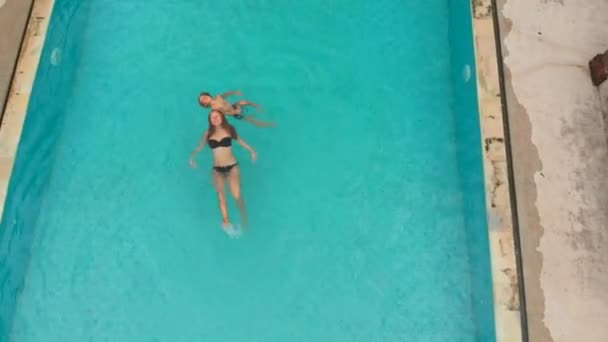 Aerial shot of a young woman and her little son tourists having a good time in a swimming pool in a tropical surrounding. Tropical life concept — ストック動画