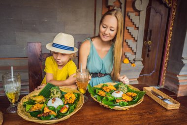 Anne ve oğul turistler Endonezya yemek kafesinde. Çocuk konseptiyle seyahat etmek. Çocuklarla ne yapılır? Çocuk dostu bir yer