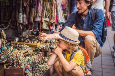 Baba ve oğlu Ubud, Bali'de bir markette. Ünlü Ubud Market, Endonezya'da Hediyelik eşya ve Bali el sanatları satan tipik hediyelik eşya dükkanı. Bali pazarı. Ahşap hediyelik eşya ve yerel el sanatları