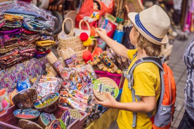Ubud, Bali'de bir markette çocuk. Ünlü Ubud Market, Endonezya'da Hediyelik eşya ve Bali el sanatları satan tipik hediyelik eşya dükkanı. Bali pazarı. Yerel sakinlerinin ahşap ve el sanatları Hediyelik eşya