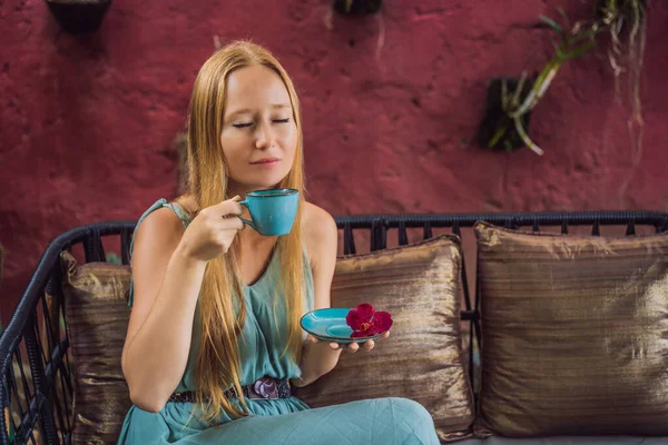 Jovem mulher tendo um café da manhã mediterrâneo sentado no sofá e bebe café aromático quente — Fotografia de Stock