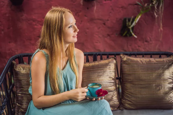Młoda kobieta przy śródziemnomorskim śniadaniu siedzi na kanapie i pije gorącą aromatyczną kawę — Zdjęcie stockowe