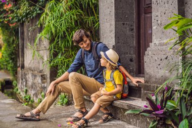 Baba ve oğul turistler Bali 'de Ubud' un dar ve rahat sokakları boyunca yürüyorlar. Bali popüler bir turizm merkezidir. Bali 'ye seyahat. Çocuk konseptiyle seyahat etmek