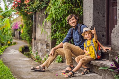 Baba ve oğul turistler Bali 'de Ubud' un dar ve rahat sokakları boyunca yürüyorlar. Bali popüler bir turizm merkezidir. Bali 'ye seyahat. Çocuk konseptiyle seyahat etmek
