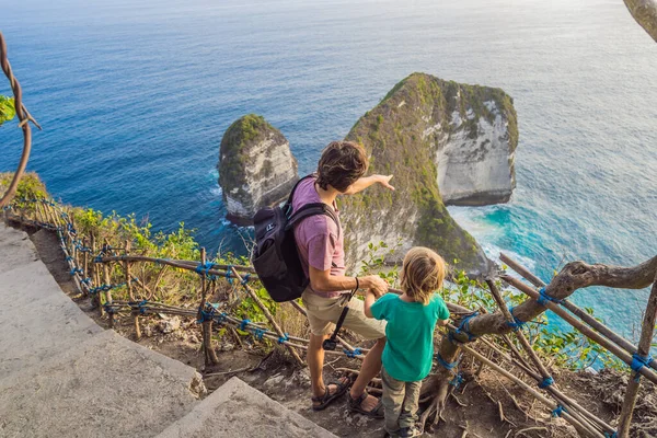 Family vacation lifestyle. Happy father and son stand at viewpoint. Look at beautiful beach under high cliff. Travel destination in Bali. Popular place to visit on Nusa Penida island — Stock Photo, Image