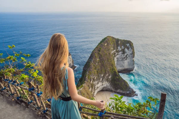 Familienurlaub. Glückliche Frau steht am Standpunkt. Blick auf schönen Strand unter hohen Klippen. Reiseziel in bali. Beliebter Ort für einen Besuch auf der Insel Nusa Penida — Stockfoto