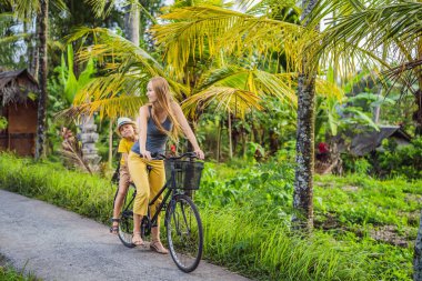 Anne ve oğlu Ubud, Bali 'de pirinç tarlasında bisiklet sürüyor. Çocuk konseptiyle Bali 'ye seyahat