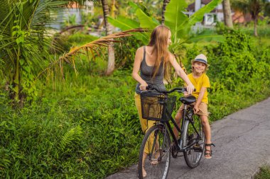 Anne ve oğlu Ubud, Bali 'de pirinç tarlasında bisiklet sürüyor. Çocuk konseptiyle Bali 'ye seyahat