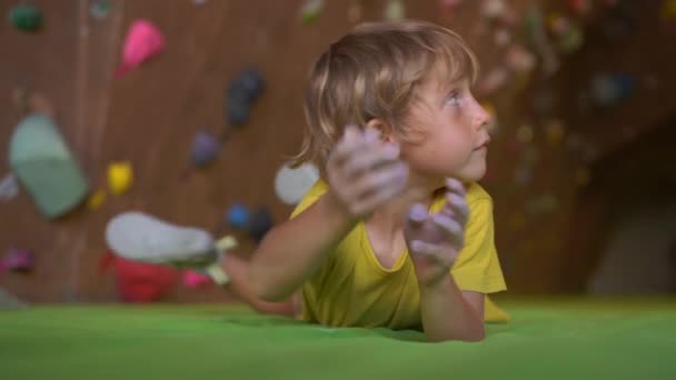 Повільний знімок маленького хлопчика піднімається на стіну в тренажерному залі для скелелазіння — стокове відео