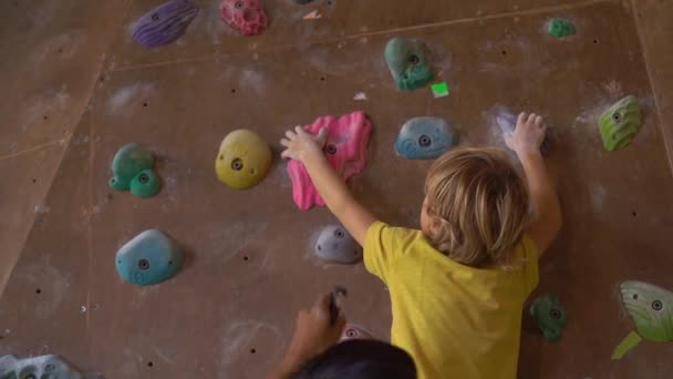 UBUD, INDONESIA - 4.08.2019: Slowmotion shot of a little boy is climbing the wall in a bouldering climbing gym — Stock Video