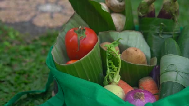 Concepto de envasado de productos ecológicos. Verduras envueltas en una hoja de plátano, como alternativa a una bolsa de plástico. Concepto de cero residuos. Envases alternativos — Vídeo de stock