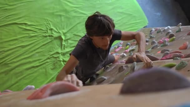 Tânărul urcă zidul într-o sală de gimnastică de alpinism — Videoclip de stoc