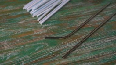 Renkli ahşap arka planda paslanmaz ve plastik pipetlerin yakın plan çekimleri. Çevre dostu alternatif kavram. Plastiksiz bir gelecek için savaş