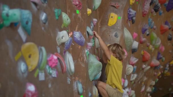 Slowmotion shot of a little boy is climbing the wall in a bouldering climbing gym — Stock Video