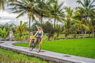 Anne ve oğlu Ubud, Bali 'de pirinç tarlasında bisiklet sürüyor. Çocuk konseptiyle Bali 'ye seyahat
