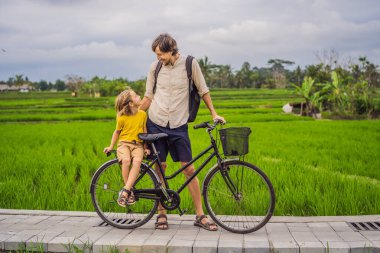 Baba oğul Ubud, Bali 'de pirinç tarlasında bisiklet sürüyorlar. Çocuk konseptiyle Bali 'ye seyahat
