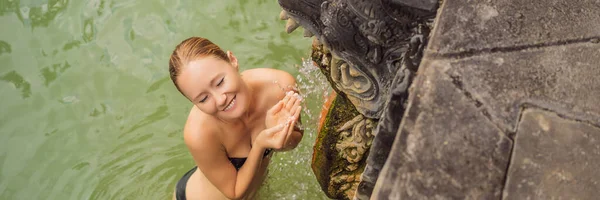 Mujer joven en banjar de aguas termales. El agua termal se libera de la boca de estatuas en una fuente termal en Banjar, Bali, Indonesia BANNER, FORMATO LARGO —  Fotos de Stock