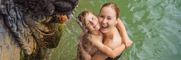 Mamma e figlio viaggiatori in terme banjar. L'acqua termale viene rilasciata dalla bocca delle statue nelle sorgenti termali di Banjar, Bali, Indonesia. Viaggiare con bambini concetto BANNER, FORMATO LUNGO — Foto Stock