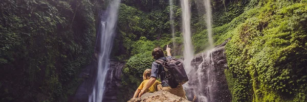 Dad and son at the Sekumpul waterfalls in jungles on Bali island, Indonesia. Bali Travel Concept BANNER, LONG FORMAT